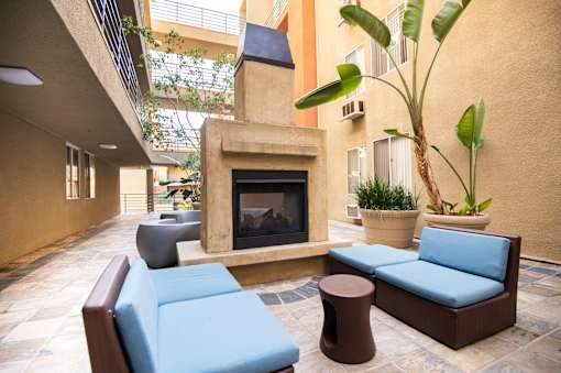 A patio with a fireplace, couch, and potted plant.