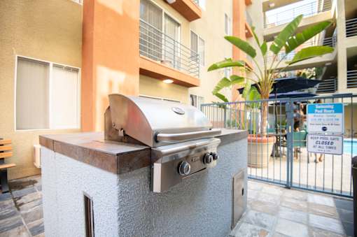 A grill is on a concrete block outside a building.