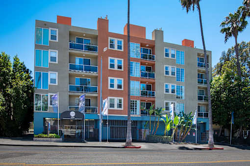 A large apartment building with balconies and flags in front.