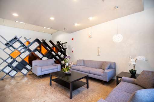 A living room with a grey couch, a black coffee table and a wall art.
