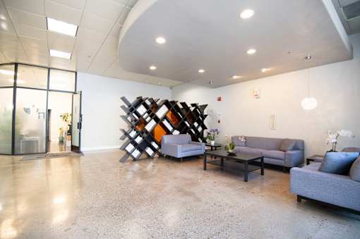 A modern living room with a grey sofa and a wooden sculpture.