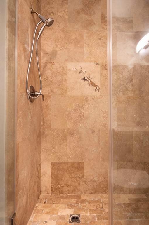 A shower with a tile floor and tiled walls.