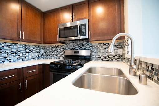 A kitchen with a stove, sink, and microwave.