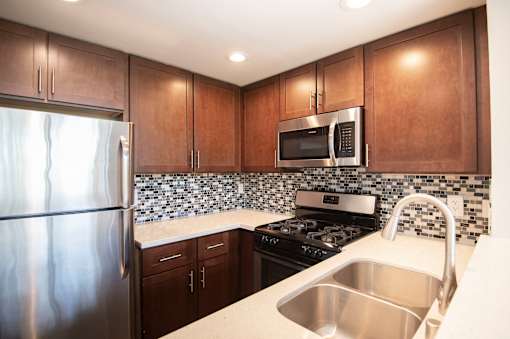 A kitchen with a stainless steel refrigerator, microwave, and stove.