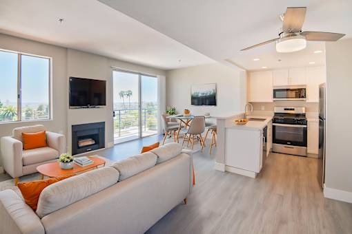 A modern living room with a fireplace and a kitchen in the background.