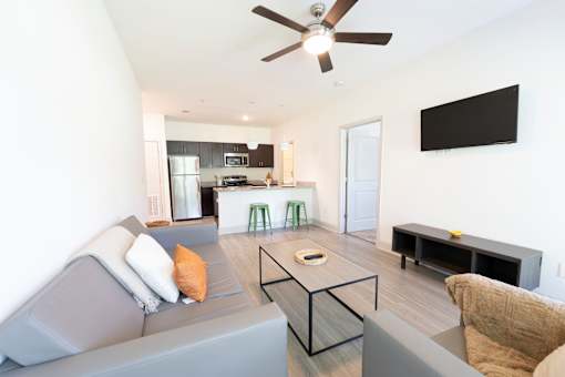 A modern living room with a grey couch and a black TV on the wall.
