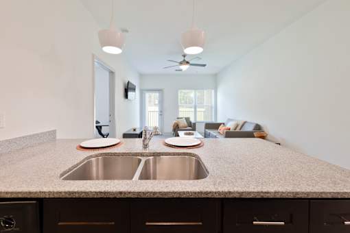 A kitchen with a granite countertop and a stainless steel sink.