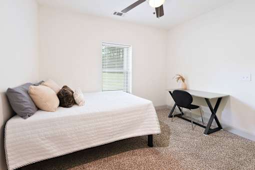 A bedroom with a bed, chair, and desk.