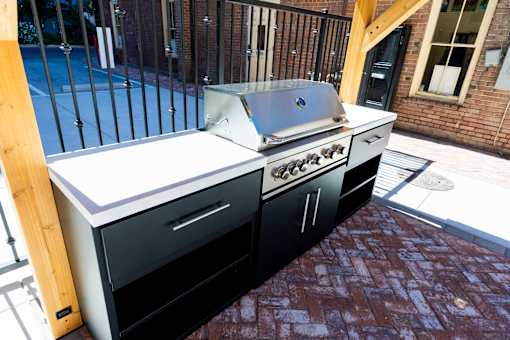 A black and white outdoor kitchen with a grill and sink.