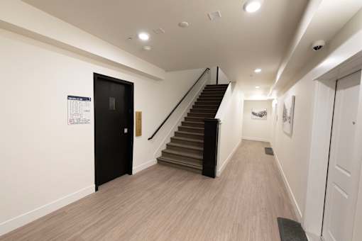 A hallway with a staircase and a door on the left side.