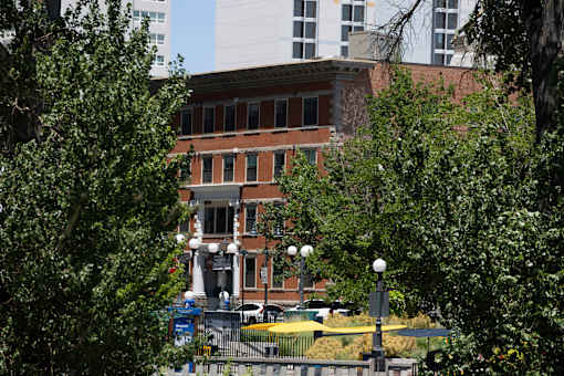 A building with a red brick facade is surrounded by trees.