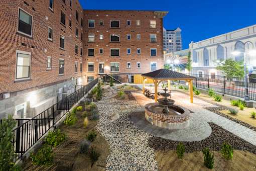 A courtyard with a fountain and a gazebo surrounded by buildings.