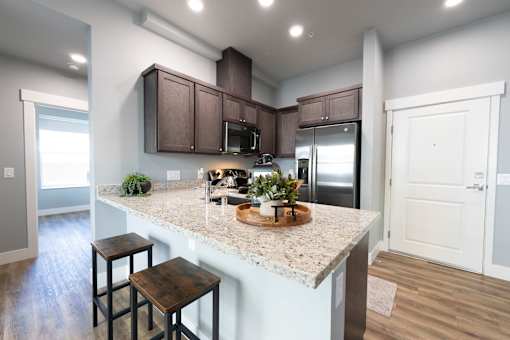 A kitchen with a granite countertop and wooden stools.
