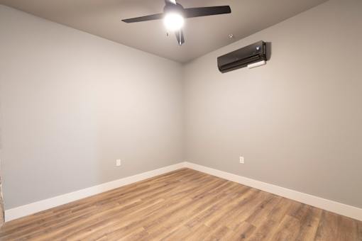 A room with a ceiling fan and an air conditioner unit on the wall.