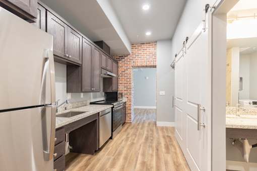 A kitchen with a refrigerator, sink, and cabinets.