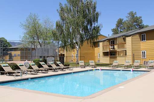 A pool with sun loungers and a yellow building in the background.