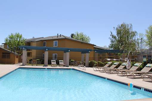 A swimming pool in front of a building with sun loungers.
