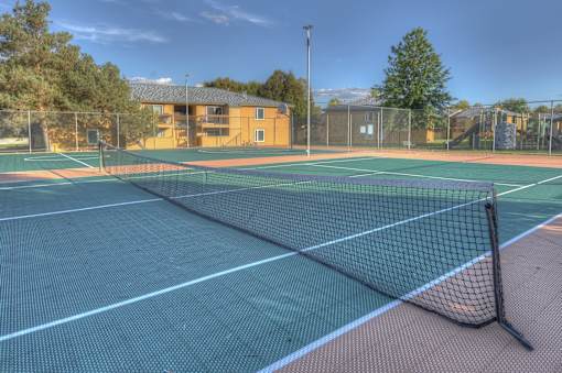 A tennis court with a green and red surface and a black net.