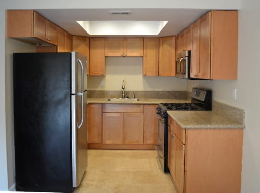View of kitchen with tile flooring, stainless appliances, and brown cabinets