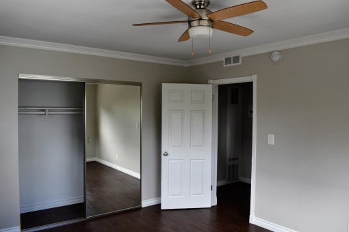 View of bedroom with wood look flooring, sliding glass mirror closet, and ceiling fan
