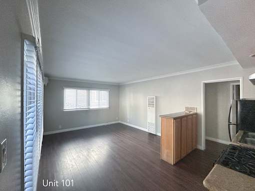 A living room with wooden floors and a window with blinds.