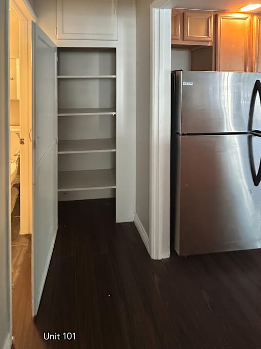 A kitchen with a stainless steel refrigerator and wooden floors.