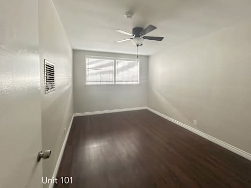 A room with a ceiling fan and wooden flooring.