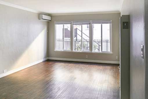 an empty living room with wood floors and a window