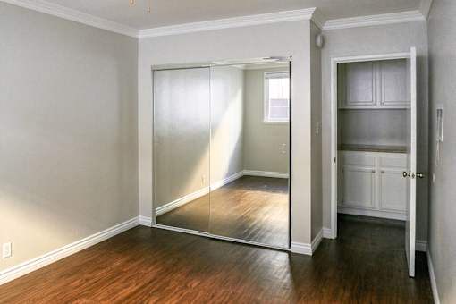 a bedroom with a mirrored closet door and a hard wood floor