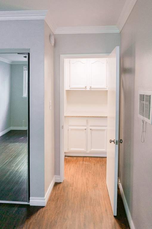 an empty room with white cabinets and a hallway to a closet