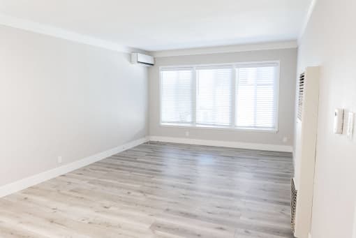 an empty room with wood floors and a window