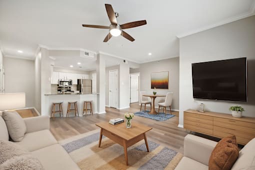 A living room with a ceiling fan and a flat screen TV.