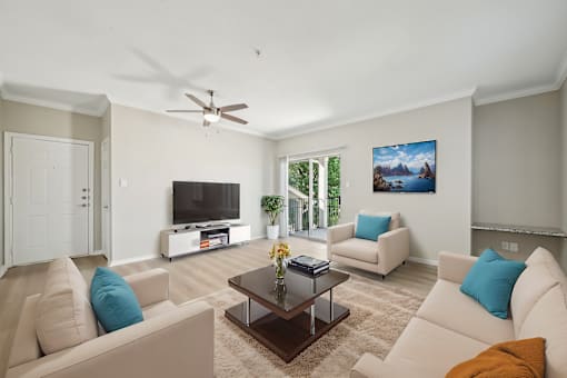 A living room with a television, two couches, and a ceiling fan.