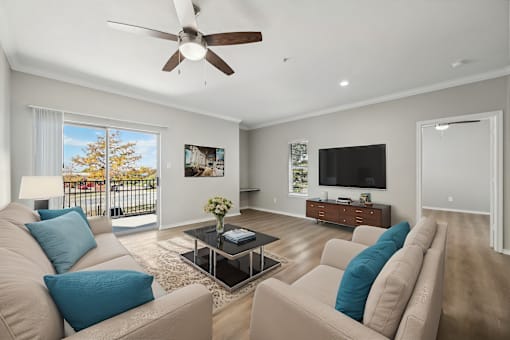 A living room with a ceiling fan and a large window.