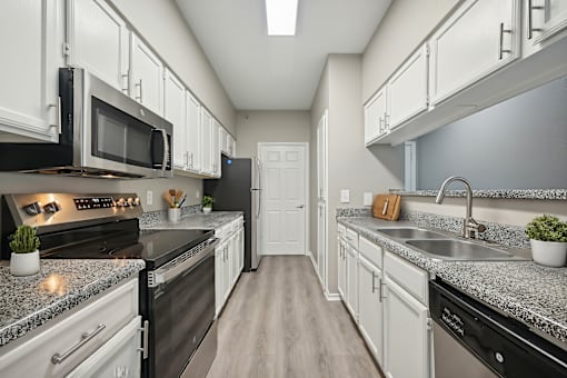 A kitchen with black appliances and white cabinets.
