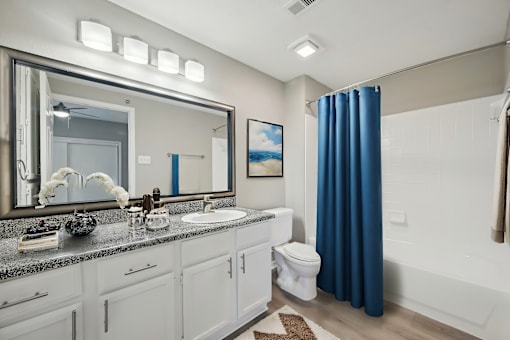 A bathroom with a white vanity and a blue shower curtain.