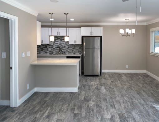 View of kitchen from living area with wood like flooring stainless appliances recessed lighting white counters