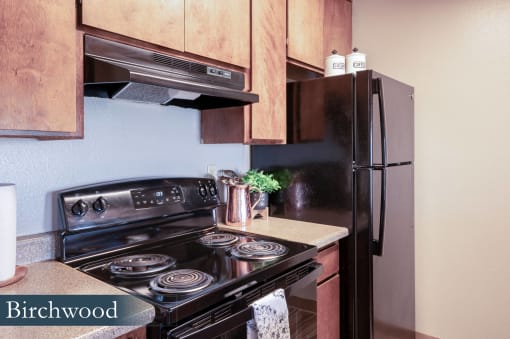 a kitchen with black appliances and wood cabinets and a refrigerator