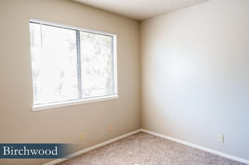 a bedroom with a large window and a carpeted floor
