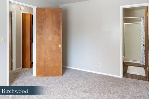 an empty room with a wooden door and a carpeted floor