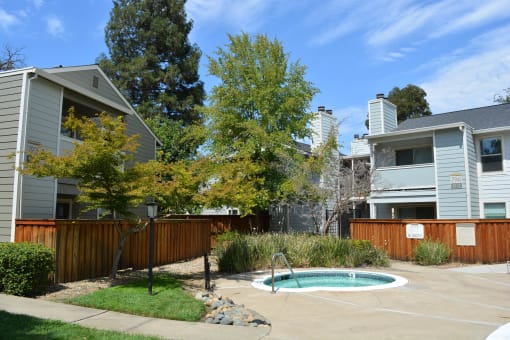 View of community spa, lush shrubbery, private patio/ balcony and exterior of buildings