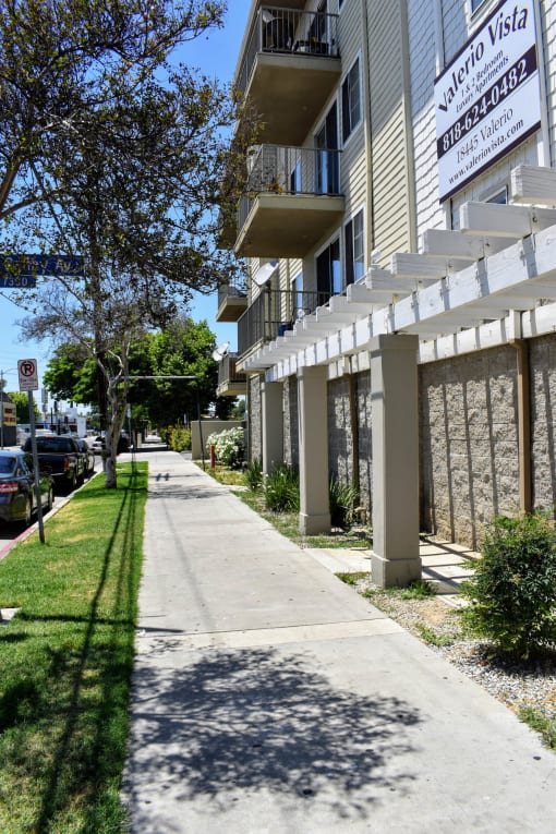 an empty sidewalk in front of an apartment building