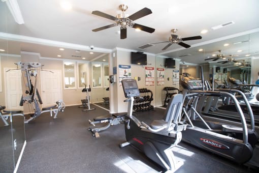 View of community gym with stationary kike, elliptical, tread mill, free weights, and weight machine