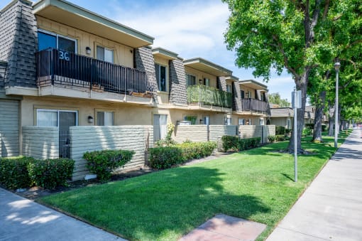 a row of apartments with balconies and green grass and trees