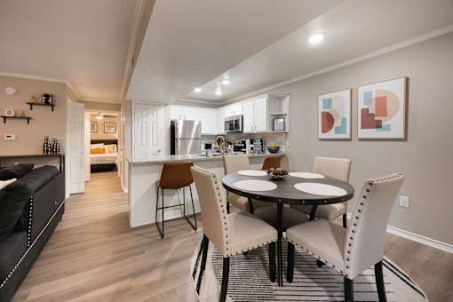A modern kitchen with a dining table set for two.