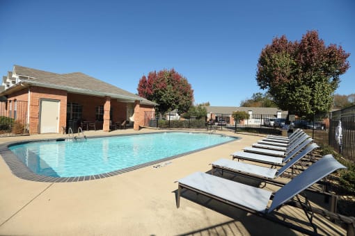 View of gated community pool with lounge chairs and access to community gym