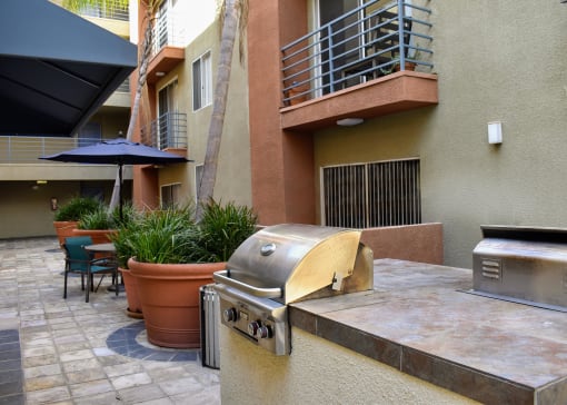 View of community grilling station with counter space to prep food, seating, and tropical plants