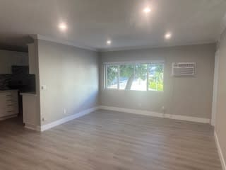 A room with a window and a wooden floor.