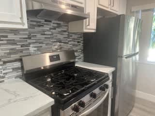 A kitchen with a black stove top oven and a black refrigerator.
