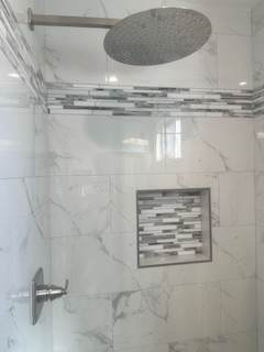 A bathroom with a marble wall and a shower.